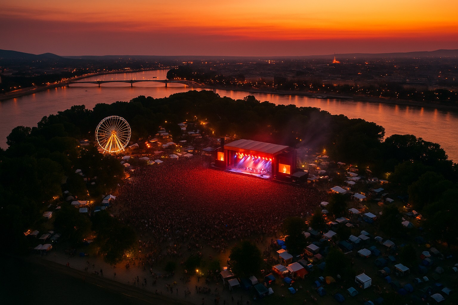Sziget Festival auf der Óbuda-Insel in Budapest: Luftaufnahme bei Sonnenuntergang zeigt die Hauptbühne mit rotem Licht, ein riesiges Publikum, ein beleuchtetes Riesenrad und den Donaufluss im Hintergrund.